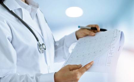 87841175-médico-de-la-mujer-mirando-y-leyendo-informes-finales-en-la-sala-de-un-hospital-de-fondo