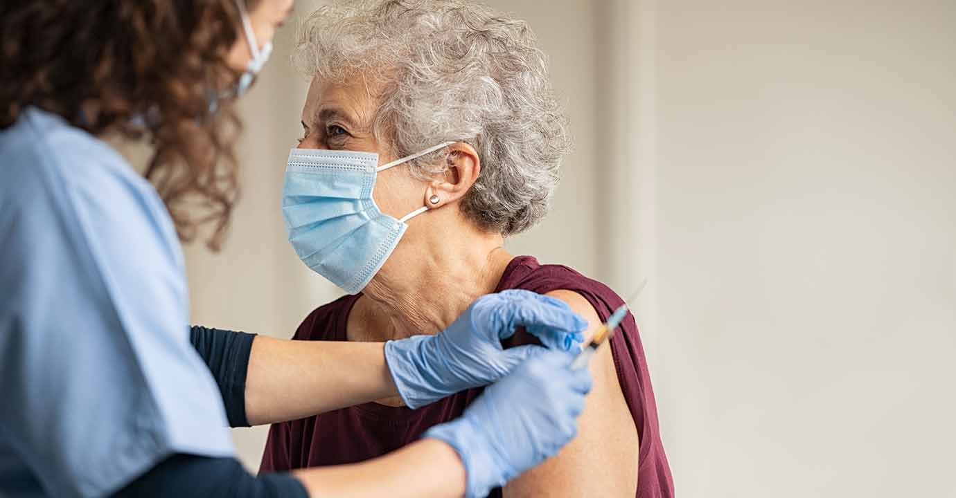Doctor giving Covid vaccine to senior woman